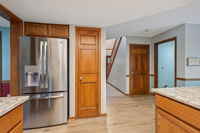7591 Creekbend Dr, Pickerington, OH 43147 - kitchen with stainless steel fridge, light wood-style floors, a textured ceiling, light stone counters, and brown cabinets
