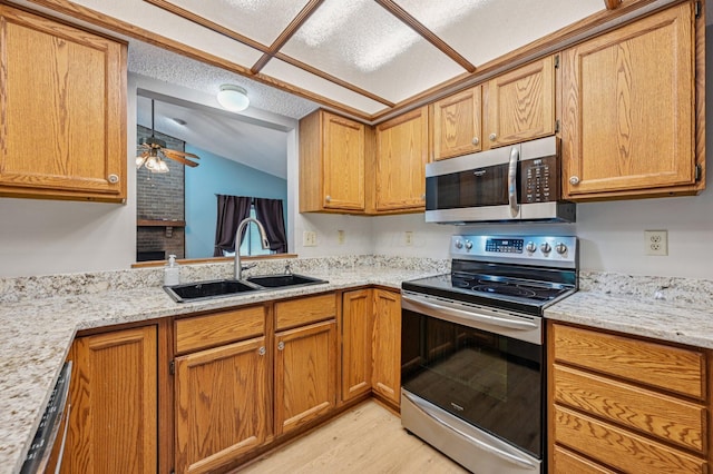 7591 Creekbend Dr, Pickerington, OH 43147 - kitchen featuring appliances with stainless steel finishes, lofted ceiling, light wood finished floors, brown cabinetry, and light stone countertops