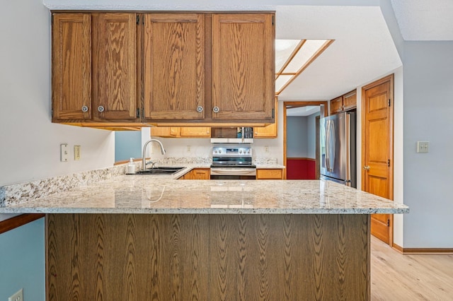 7591 Creekbend Dr, Pickerington, OH 43147 - kitchen featuring stainless steel appliances, light wood finished floors, a peninsula, light stone countertops, and brown cabinets