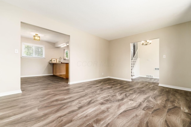 5032 Labelle Dr, Columbus, OH 43232 - unfurnished living room featuring a chandelier, wood finished floors, and stairs