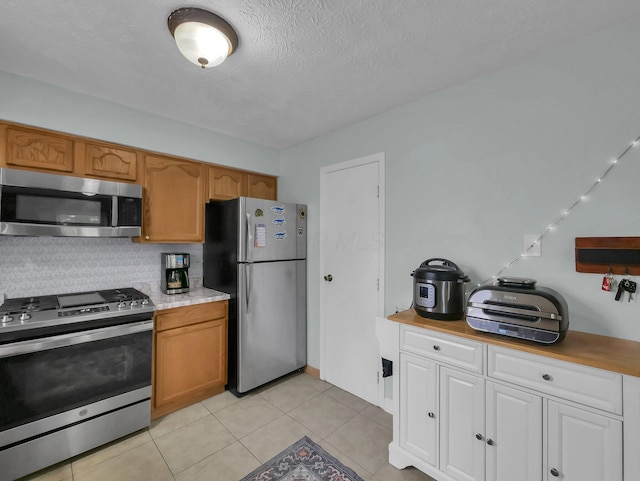 4809 King Albert Dr Unit 1A, Hilliard, OH 43026 - kitchen featuring stainless steel appliances, light countertops, decorative backsplash, a textured ceiling, and light tile patterned flooring