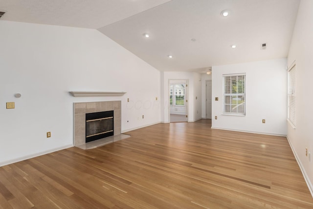 8209 Farm Crossing Cir, Powell, OH 43065 - unfurnished living room with lofted ceiling, a tile fireplace, light wood finished floors, and recessed lighting
