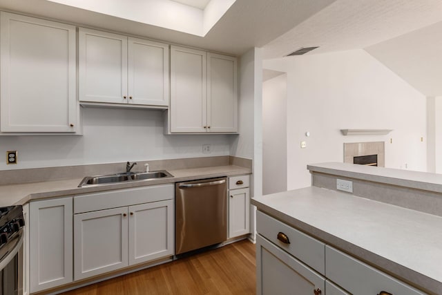 8209 Farm Crossing Cir, Powell, OH 43065 - kitchen with stainless steel appliances, light wood-type flooring, a tiled fireplace, light countertops, and gray cabinetry