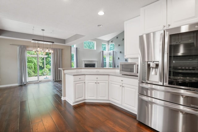 8020 Glenmore Dr, Powell, OH 43065 - kitchen featuring stainless steel appliances, a peninsula, a chandelier, a fireplace, and dark wood finished floors