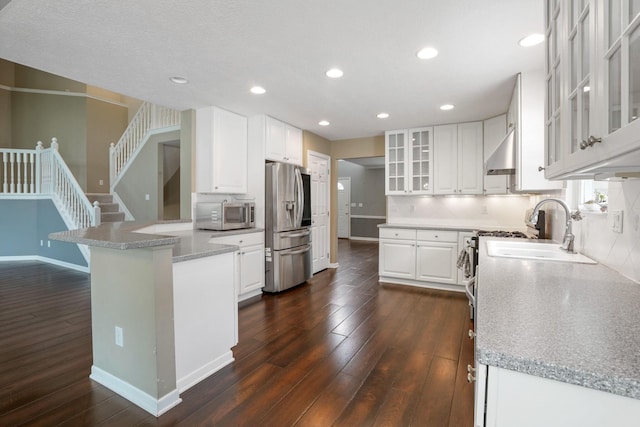 8020 Glenmore Dr, Powell, OH 43065 - kitchen with stainless steel appliances, under cabinet range hood, dark wood finished floors, a peninsula, and recessed lighting