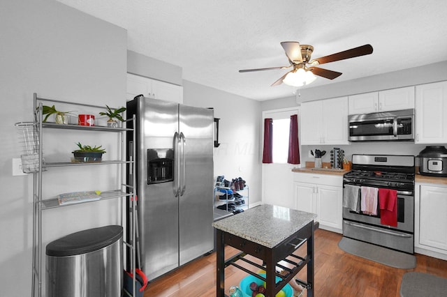 3101 Lewis Rd, Columbus, OH 43207 - kitchen with appliances with stainless steel finishes, a ceiling fan, white cabinets, dark wood finished floors, and a textured ceiling