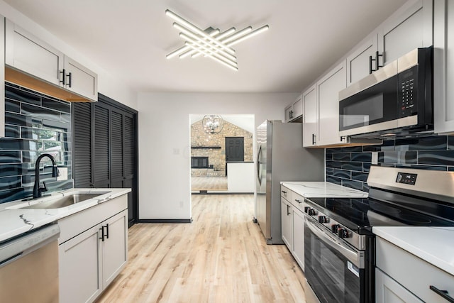 340 Danhurst Rd, Columbus, OH 43228 - kitchen with appliances with stainless steel finishes, tasteful backsplash, light wood finished floors, a chandelier, and light stone counters