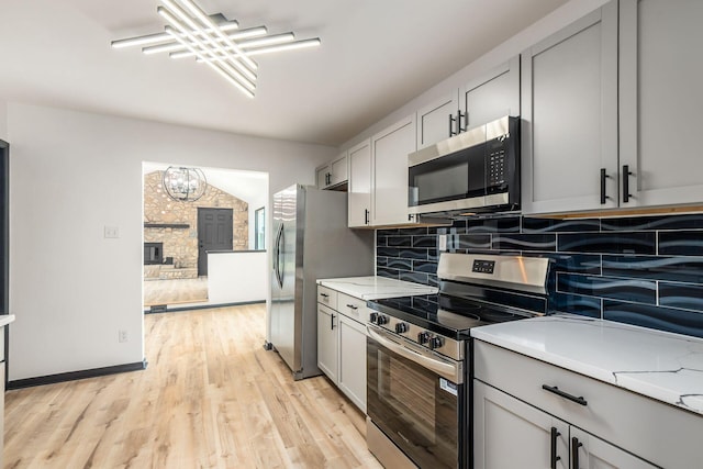 340 Danhurst Rd, Columbus, OH 43228 - kitchen featuring stainless steel appliances, gray cabinets, light countertops, backsplash, and light wood-style flooring