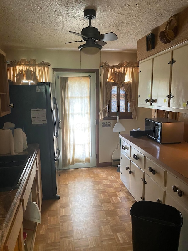 12170 Fairview Rd SE, Heath, OH 43056 - kitchen with stainless steel microwave, white cabinetry, a ceiling fan, freestanding refrigerator, and a textured ceiling