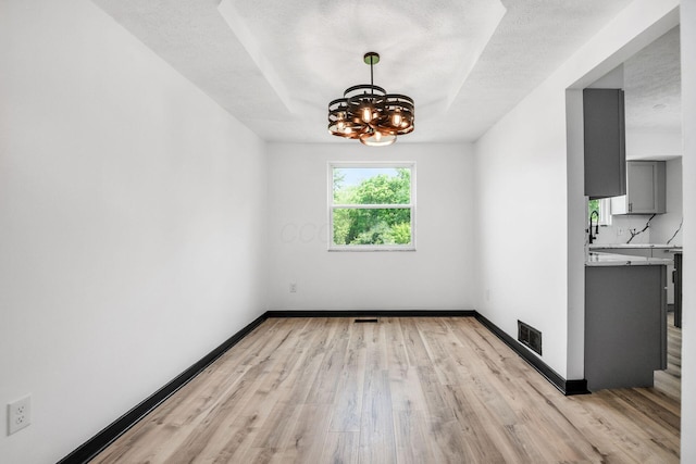 2840 Harnet Ct, Columbus, OH 43231 - unfurnished dining area featuring a chandelier, light wood-style flooring, and a textured ceiling