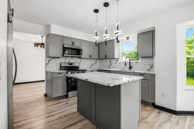 2840 Harnet Ct, Columbus, OH 43231 - kitchen featuring appliances with stainless steel finishes, gray cabinetry, decorative backsplash, light wood-style floors, and light stone countertops
