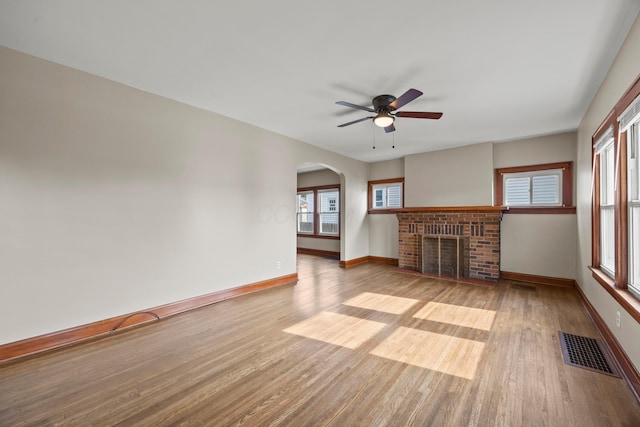 685 S Hague Ave, Columbus, OH 43204 - unfurnished living room featuring wood finished floors, ceiling fan, a brick fireplace, and arched walkways