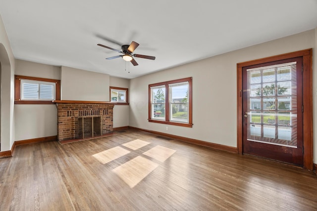 685 S Hague Ave, Columbus, OH 43204 - unfurnished living room with light wood-type flooring, ceiling fan, a brick fireplace, and arched walkways