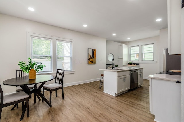 1233 Oakwood Ave, Columbus, OH 43206 - kitchen with stainless steel appliances, light wood-style floors, recessed lighting, a kitchen island with sink, and white cabinetry