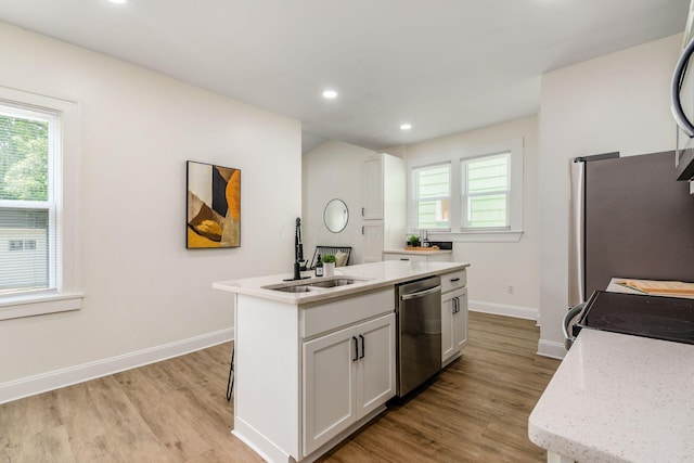 1233 Oakwood Ave, Columbus, OH 43206 - kitchen with appliances with stainless steel finishes, light wood-style flooring, white cabinets, a center island with sink, and recessed lighting