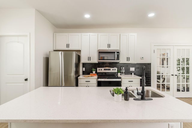 1233 Oakwood Ave, Columbus, OH 43206 - kitchen with stainless steel appliances, tasteful backsplash, light stone countertops, an island with sink, and white cabinets