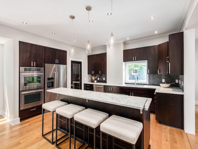 248 E Whittier St, Columbus, OH 43206 - kitchen featuring appliances with stainless steel finishes, decorative backsplash, a kitchen breakfast bar, dark brown cabinetry, and crown molding