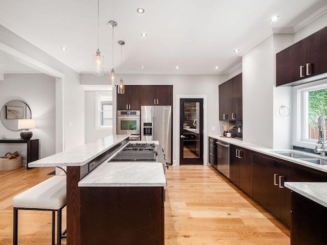 248 E Whittier St, Columbus, OH 43206 - kitchen featuring appliances with stainless steel finishes, a kitchen island, a kitchen bar, dark brown cabinetry, and light wood-style flooring