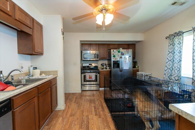 1935 Sedan Ave, Obetz, OH 43207 - kitchen with appliances with stainless steel finishes, light wood-style floors, ceiling fan, and brown cabinetry