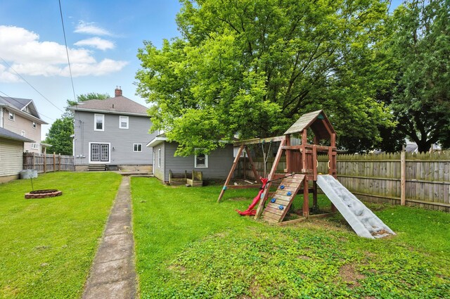 835 Rogers St, Bucyrus, OH 44820 - back of property with a fenced backyard, a fire pit, a playground, and a chimney