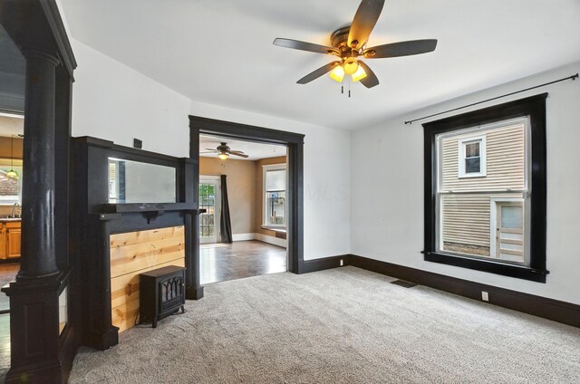 835 Rogers St, Bucyrus, OH 44820 - unfurnished living room featuring carpet flooring, ceiling fan, and a wood stove