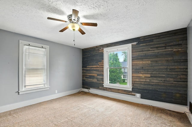 835 Rogers St, Bucyrus, OH 44820 - spare room featuring wooden walls, a ceiling fan, a textured ceiling, carpet floors, and an accent wall