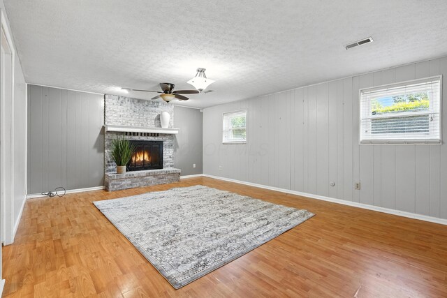 65 Jeffery Ln SE, Heath, OH 43056 - living room featuring a ceiling fan, a textured ceiling, light wood-style flooring, a brick fireplace, and wood walls