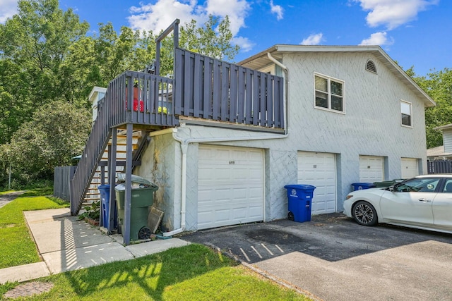 699 Cherry Hollow Rd Unit A, Columbus, OH 43228 - view of side of home featuring a garage, asphalt driveway, stucco siding, and stairway
