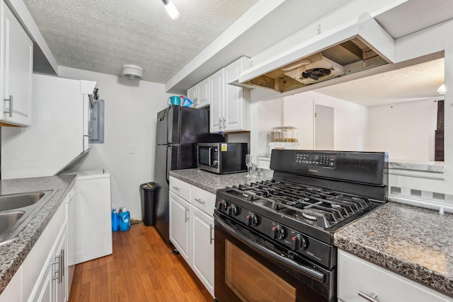 699 Cherry Hollow Rd Unit A, Columbus, OH 43228 - kitchen featuring black appliances, a textured ceiling, custom exhaust hood, white cabinets, and light wood finished floors