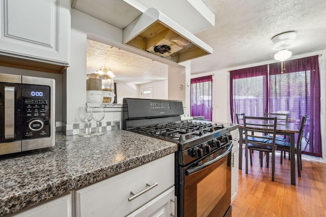 699 Cherry Hollow Rd Unit A, Columbus, OH 43228 - kitchen featuring black gas stove, a textured ceiling, white cabinets, stainless steel microwave, and dark countertops