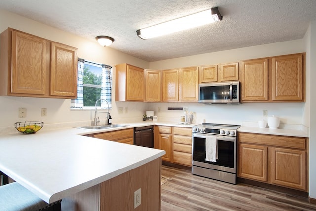 237 Harvard Loop, Delaware, OH 43015 - kitchen with stainless steel appliances, a peninsula, light countertops, light wood-style floors, and a textured ceiling