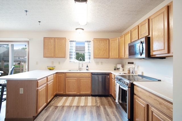 237 Harvard Loop, Delaware, OH 43015 - kitchen with appliances with stainless steel finishes, a peninsula, light wood-style flooring, a textured ceiling, and light countertops