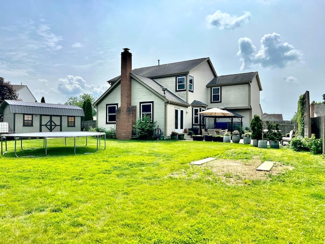 8576 Army Pl, Galloway, OH 43119 - rear view of house with a trampoline, an outdoor living space, a fenced backyard, a gazebo, and an outbuilding