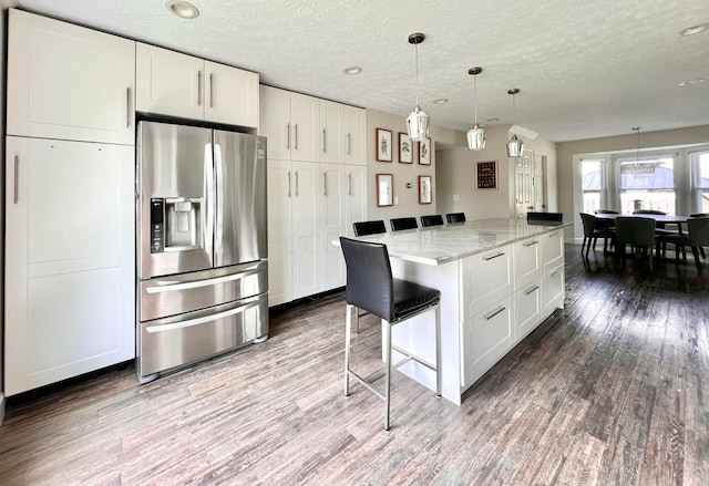 8576 Army Pl, Galloway, OH 43119 - kitchen with stainless steel fridge with ice dispenser, dark wood finished floors, a textured ceiling, white cabinets, and light stone counters