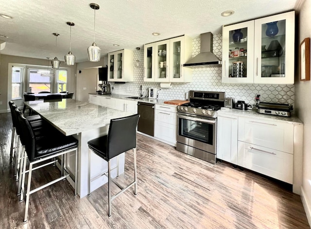 8576 Army Pl, Galloway, OH 43119 - kitchen with wall chimney range hood, stainless steel gas range, dishwashing machine, light wood finished floors, and a textured ceiling