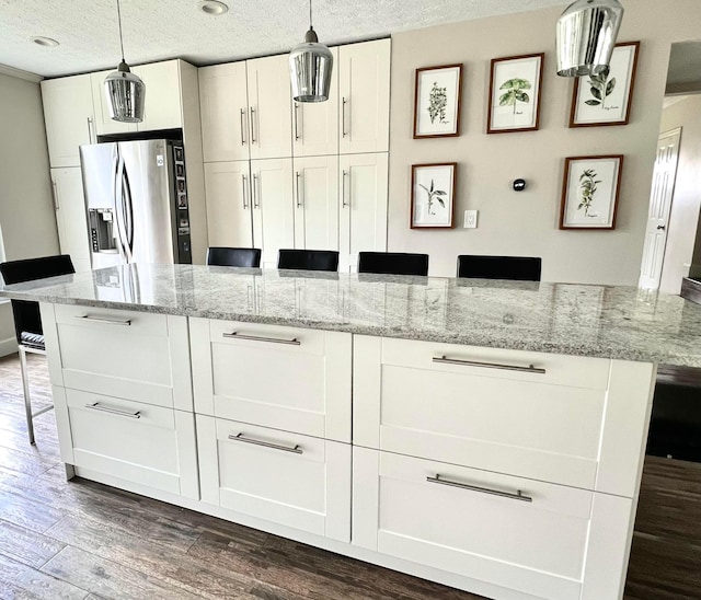 8576 Army Pl, Galloway, OH 43119 - kitchen with stainless steel fridge, dark wood finished floors, white cabinetry, a textured ceiling, and pendant lighting