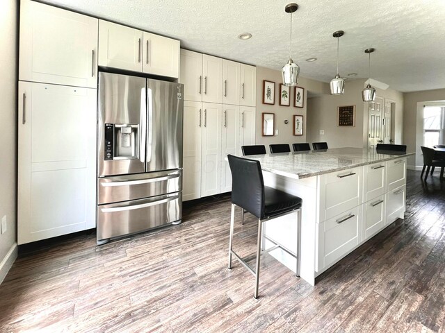 8576 Army Pl, Galloway, OH 43119 - kitchen with stainless steel fridge, dark wood-style flooring, a textured ceiling, light stone countertops, and a breakfast bar