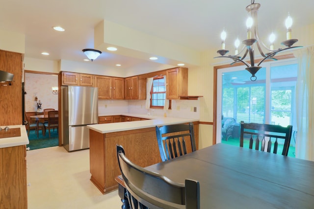 249 Orchard View Dr NE, Lancaster, OH 43130 - kitchen featuring freestanding refrigerator, brown cabinetry, a chandelier, a peninsula, and light countertops