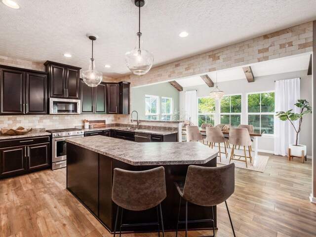153 Shawnee Dr, Pickerington, OH 43147 - kitchen featuring stainless steel appliances, a textured ceiling, a kitchen island, a kitchen breakfast bar, and tasteful backsplash