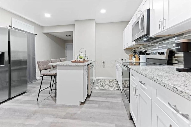 387 N Garfield Ave, Columbus, OH 43203 - kitchen featuring stainless steel appliances, a kitchen bar, light wood finished floors, white cabinets, and recessed lighting