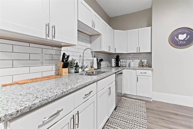 387 N Garfield Ave, Columbus, OH 43203 - kitchen featuring white cabinetry, light stone countertops, backsplash, and light wood-type flooring