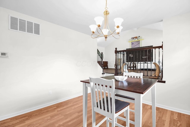 1121 Afton Rd, Columbus, OH 43221 - dining room featuring wood finished floors, a chandelier, stairway, and lofted ceiling
