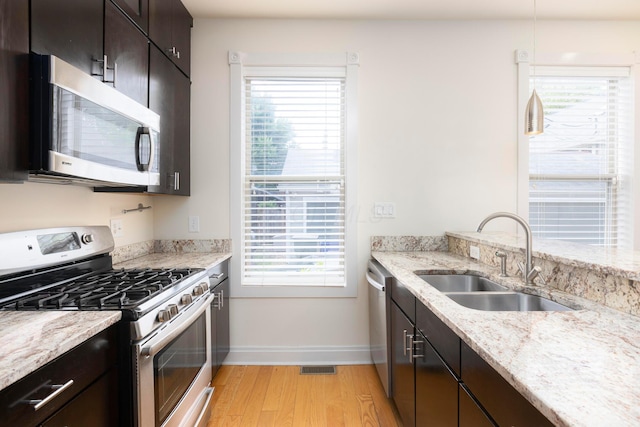 318 Berger Aly, Columbus, OH 43206 - kitchen featuring appliances with stainless steel finishes, light wood-type flooring, light stone countertops, and dark brown cabinets
