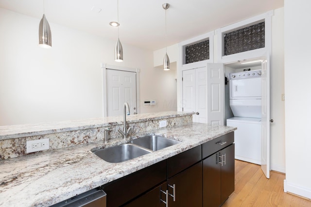 318 Berger Aly, Columbus, OH 43206 - kitchen with stacked washer and clothes dryer, light wood-type flooring, pendant lighting, light stone counters, and stainless steel dishwasher