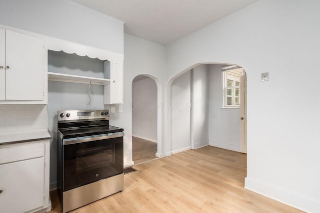 424 S Harris Ave, Columbus, OH 43204 - kitchen with stainless steel electric stove, arched walkways, white cabinetry, light wood-style floors, and tasteful backsplash