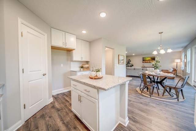 66 Genoa Cir, Commercial Point, OH 43116 - kitchen featuring open floor plan, dark wood finished floors, white cabinets, light stone counters, and hanging light fixtures