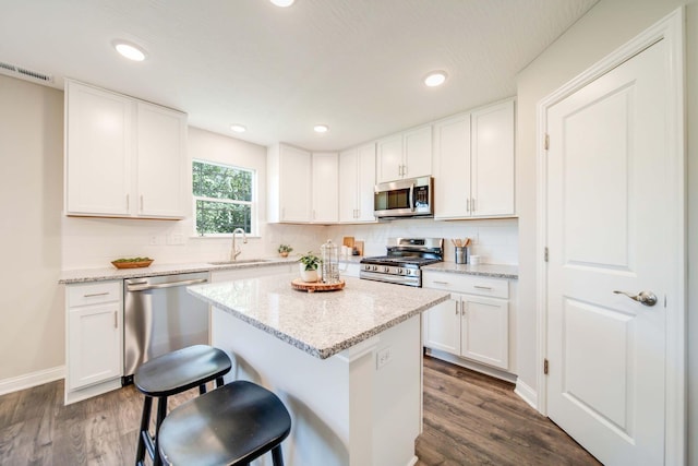 66 Genoa Cir, Commercial Point, OH 43116 - kitchen featuring appliances with stainless steel finishes, dark wood finished floors, a kitchen island, white cabinets, and recessed lighting