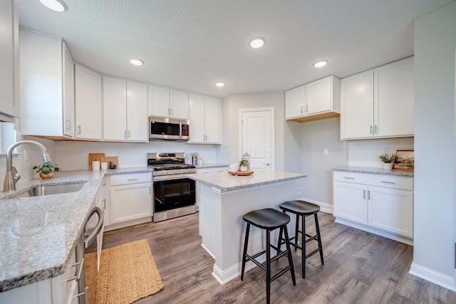 66 Genoa Cir, Commercial Point, OH 43116 - kitchen featuring stainless steel appliances, white cabinets, wood finished floors, light stone countertops, and recessed lighting