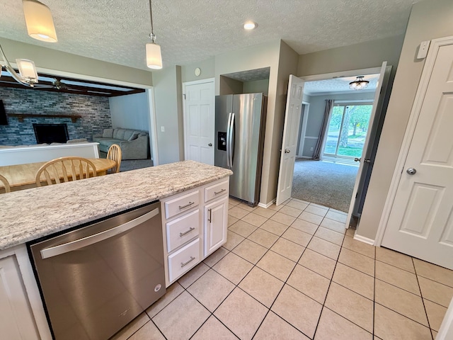 1724 Ramblewood Ave, Columbus, OH 43235 - kitchen featuring appliances with stainless steel finishes, light tile patterned flooring, white cabinetry, a textured ceiling, and hanging light fixtures
