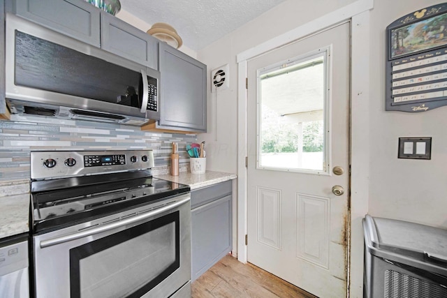 136 Ridgeview Ct, Johnstown, OH 43031 - kitchen with stainless steel appliances, gray cabinets, decorative backsplash, light wood-type flooring, and a textured ceiling